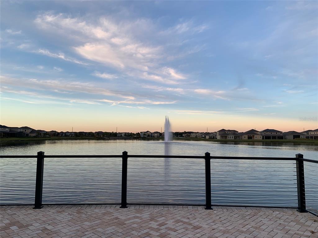 A view of a lake with a fountain, seen from a paved patio with railings — 2860 CHANTILLY AVENUE, KISSIMMEE, FL