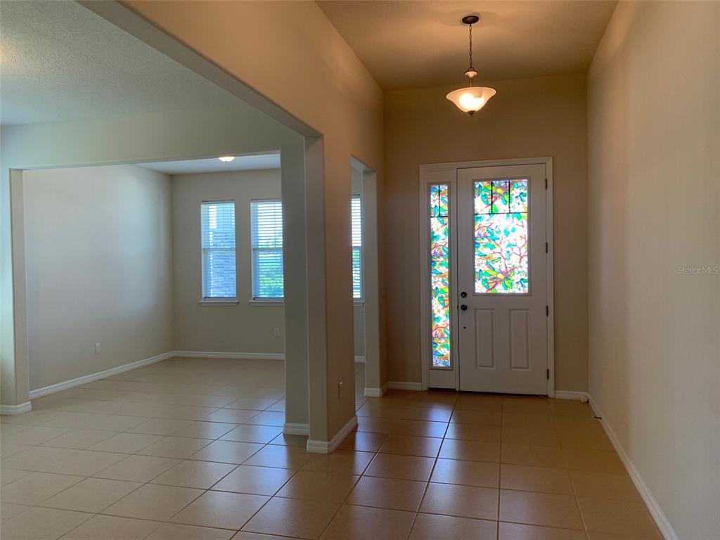 An entryway with tile flooring leads to a living area with two windows — 2860 CHANTILLY AVENUE, KISSIMMEE, FL
