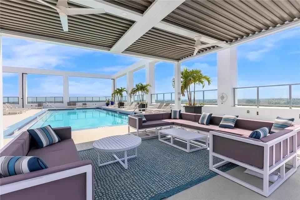A covered outdoor lounge area features modern furniture, a swimming pool, and a panoramic view — 260 S OSCEOLA AVENUE UNIT 709, ORLANDO, FL