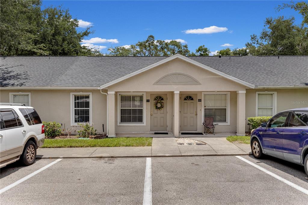 The exterior of a single-story residential building features two front doors and a parking lot — 696 S GRAND HIGHWAY, CLERMONT, FL