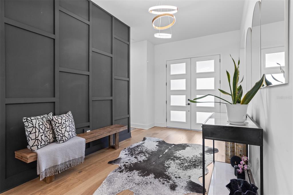 An entryway features a dark paneled accent wall, a wooden bench, and a cowhide rug — 3306 W VAN BUREN DRIVE, TAMPA, FL