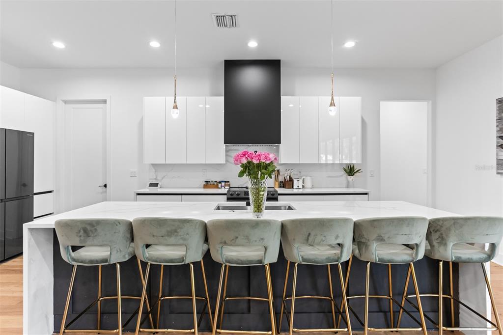 A modern kitchen features a large white island with six velvet stools and white cabinetry — 3306 W VAN BUREN DRIVE, TAMPA, FL