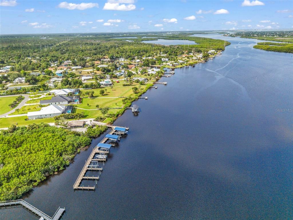 An aerial view shows a residential neighborhood bordering a river with a long boat dock — 28975 SMUGGLERS LANE, PUNTA GORDA, FL