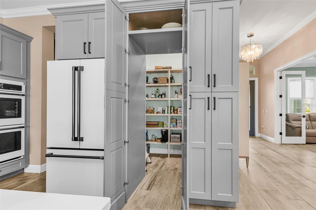 A kitchen features a white refrigerator flanked by grey cabinetry and an open walk-in pantry — 28975 SMUGGLERS LANE, PUNTA GORDA, FL
