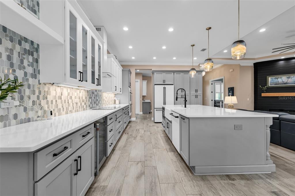 A modern kitchen features gray cabinets, white countertops, a large island, and hexagonal tile backsplashes — 28975 SMUGGLERS LANE, PUNTA GORDA, FL