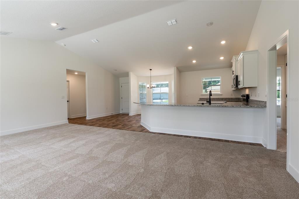 A spacious open-concept living area features gray carpeting, a kitchen with wood cabinets, and dining — 21 RICHMOND DRIVE, PALM COAST, FL