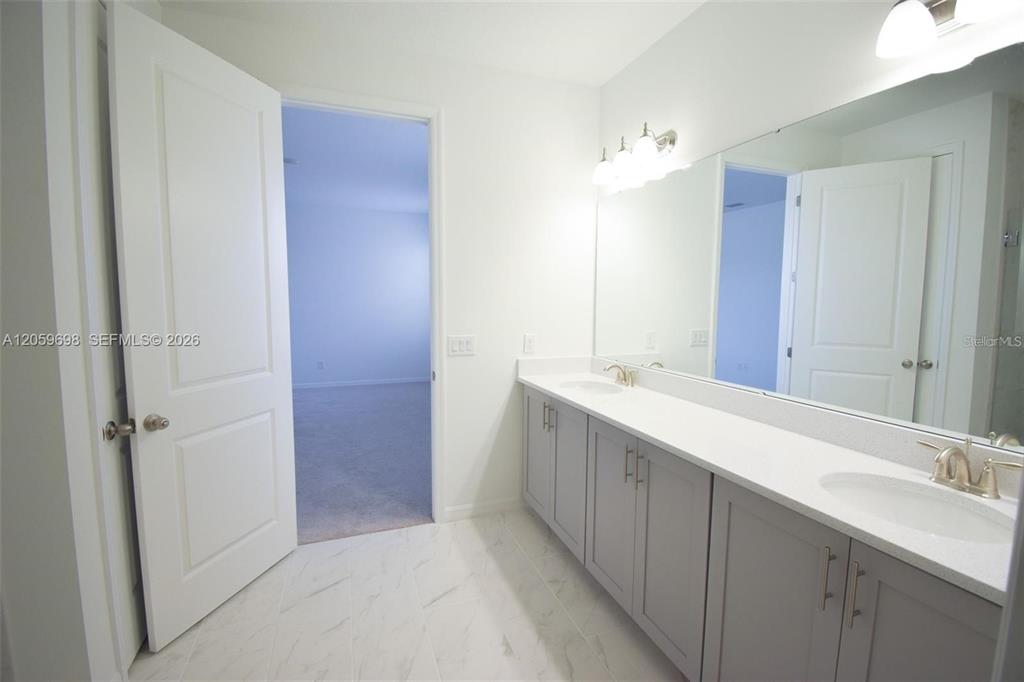 A bathroom features a double vanity with gray cabinets, white countertops, and a large mirror — 2370 LANCASHIRE STREET, DAVENPORT, FL