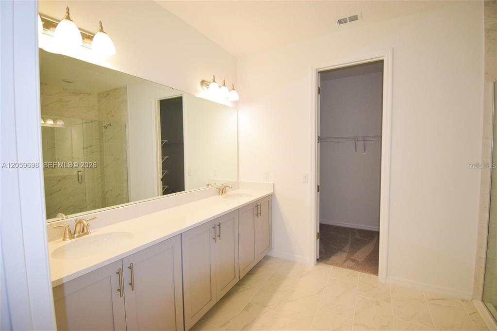 A bathroom features a double vanity with gray cabinets, white countertops, and a large mirror — 2370 LANCASHIRE STREET, DAVENPORT, FL