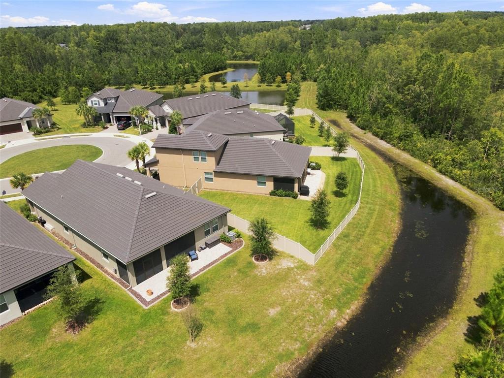 An aerial view shows several suburban houses with dark roofs situated near a winding canal — 17254 MANGO SHAY COURT, LAND O LAKES, FL