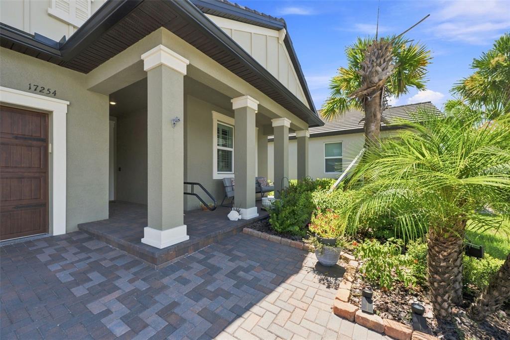 A paved walkway leads to a covered front porch with columns and a wooden door — 17254 MANGO SHAY COURT, LAND O LAKES, FL