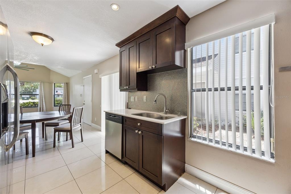 A kitchen area with dark wood cabinets, a stainless steel dishwasher, and a dining table nearby — 3023 RIO GRANDE TRAIL UNIT 3023, KISSIMMEE, FL
