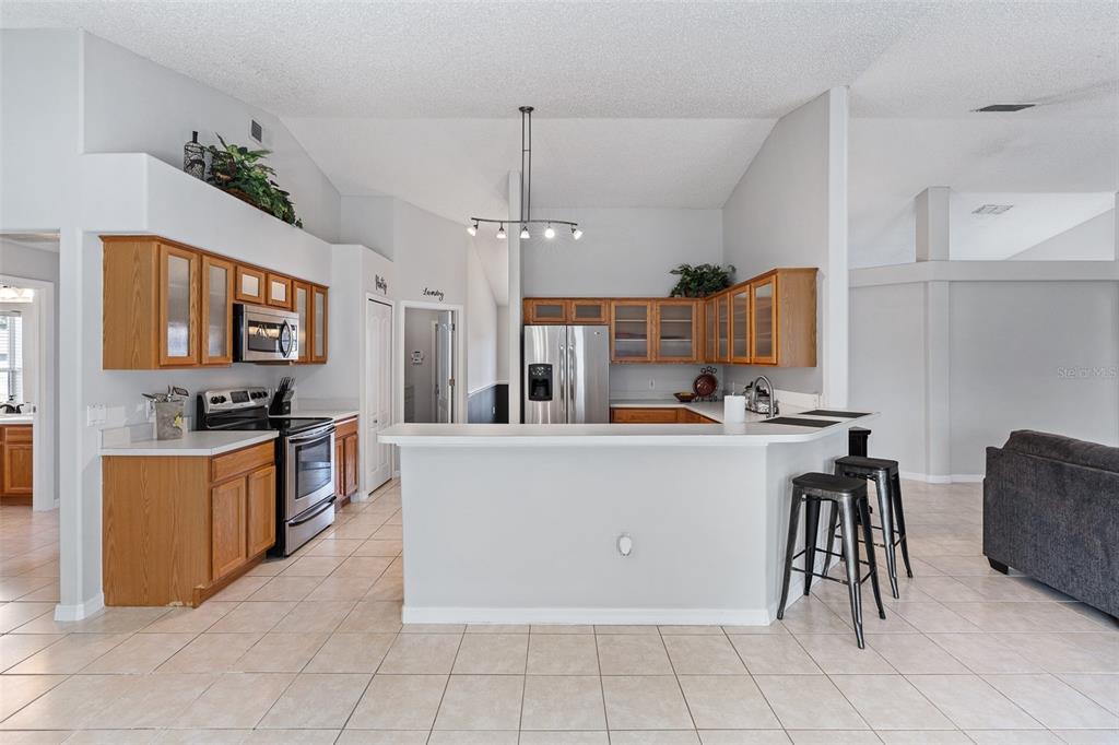 A kitchen with wood cabinets, stainless steel appliances, a breakfast bar, and tile flooring — 1928 EDEN DRIVE, DELTONA, FL
