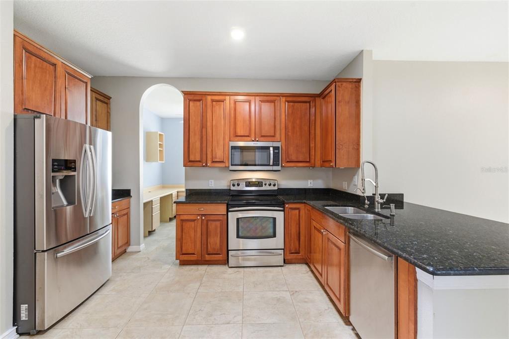 A kitchen with wood cabinets, stainless steel appliances, and dark granite countertops — 1623 CROSSVINE COURT, TRINITY, FL