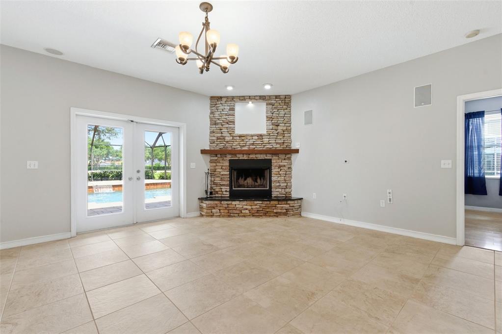 A living room features tile flooring, a stone corner fireplace, and glass doors to a pool — 1623 CROSSVINE COURT, TRINITY, FL