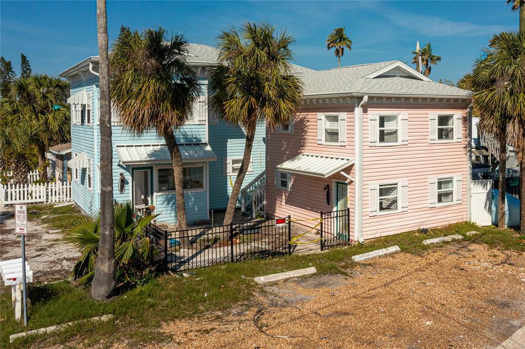 A two-story house with blue and pink siding stands behind a black metal fence — 134 86TH AVENUE, TREASURE ISLAND, FL