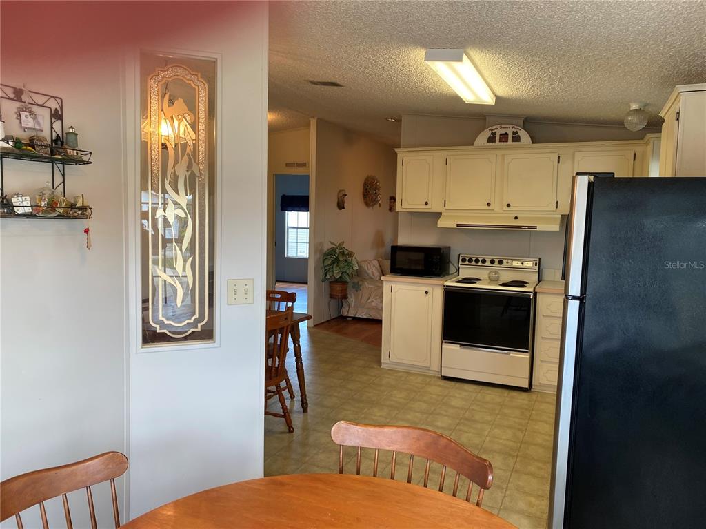A view from a dining area looking into a kitchen with white cabinets and appliances — 701 RIVERVIEW CIRCLE, NORTH PORT, FL