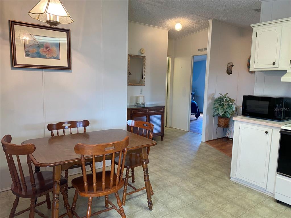 A dining area with a wooden table and chairs sits adjacent to a kitchen — 701 RIVERVIEW CIRCLE, NORTH PORT, FL