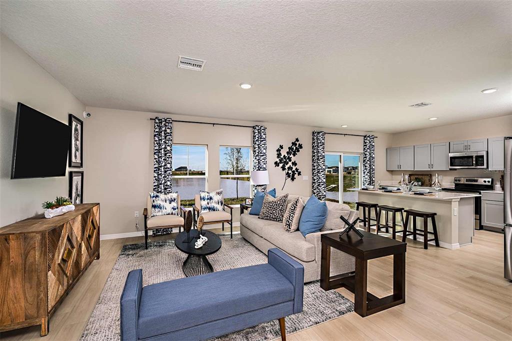An open-concept living room and kitchen featuring light wood flooring and a view of water — 15201 MAUDE LANDING LOOP, WIMAUMA, FL