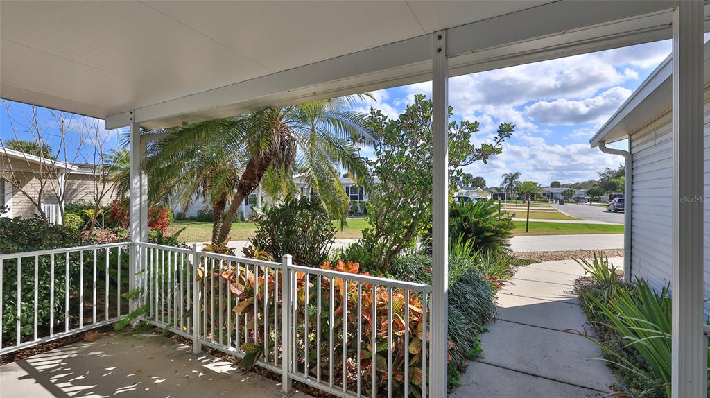 A covered porch with a white railing overlooks a landscaped yard and a neighborhood street — 361 MARSH LANDING LOOP, OAK HILL, FL