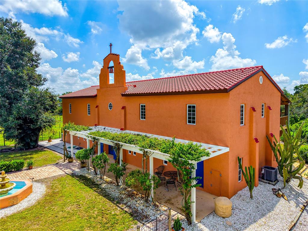 A peach-colored building with a bell gable and blue doors sits at the end of a walkway — 19600 E STATE ROAD 64, BRADENTON, FL