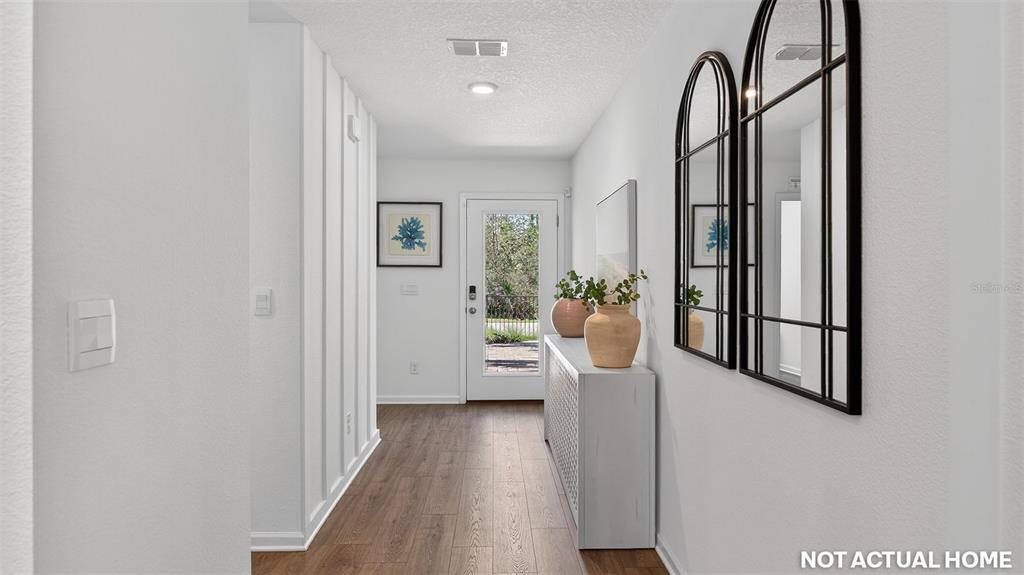 A bright entryway features white walls, wood-look flooring, a console table, and arched wall mirrors — 13 MULLIGAN WAY, BUNNELL, FL