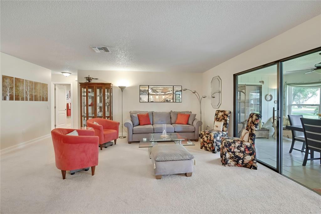 The rear exterior of a single-story house features a paved patio, lawn, and multiple windows — 6433 LOST TREE LANE, SPRING HILL, FL