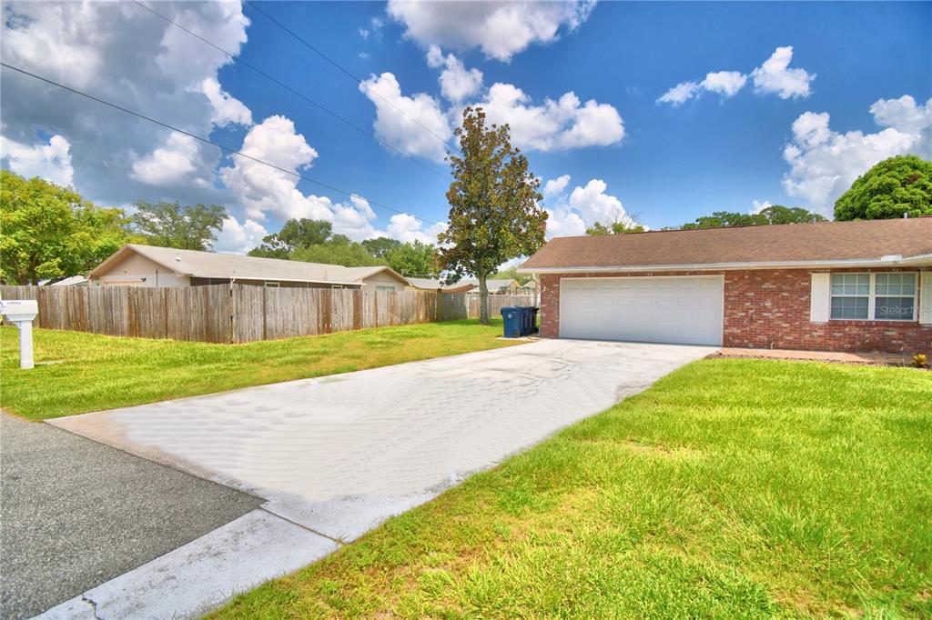 A brick house with a white garage door and a concrete driveway under a blue sky — 1206 SUSAN LANE, AUBURNDALE, FL