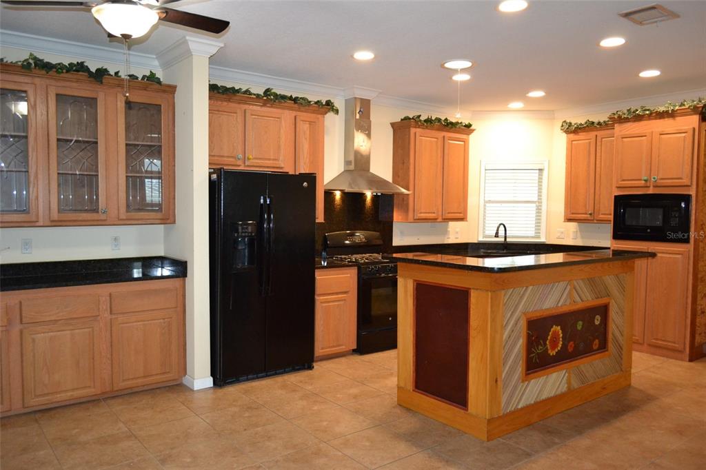 A kitchen features light wood cabinets, black appliances, a central island, and dark granite countertops — 3531 70TH AVENUE E, ELLENTON, FL