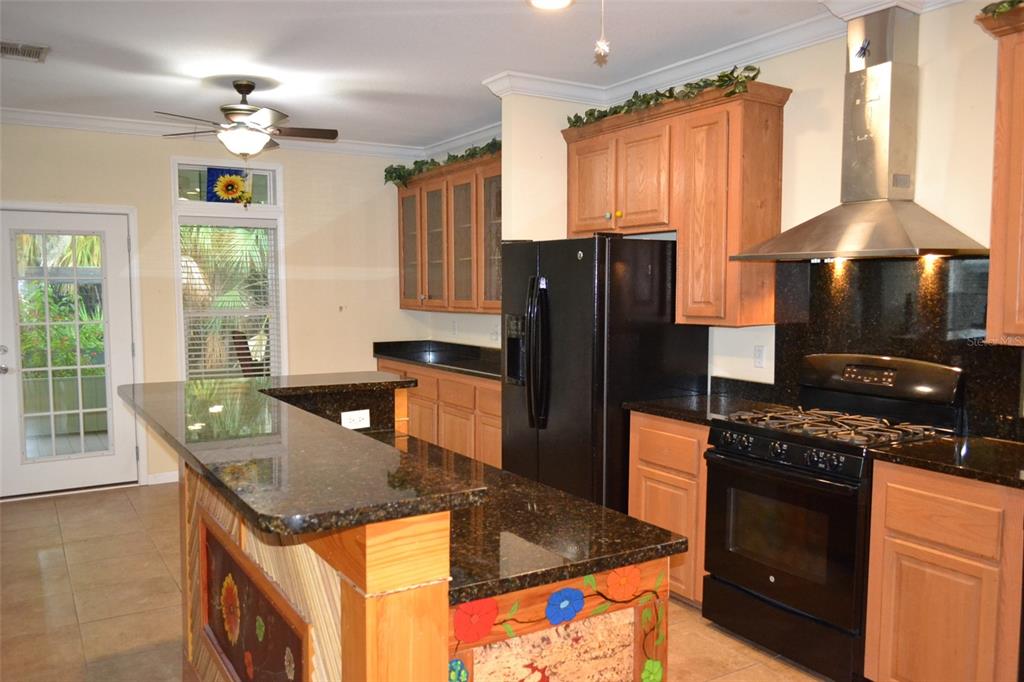 A kitchen features wood cabinets, dark granite countertops, a black refrigerator, and a gas range — 3531 70TH AVENUE E, ELLENTON, FL