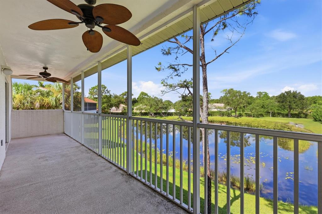 A screened-in porch with ceiling fans overlooks a pond and green landscape — 7644 MARSH ORCHID CIRCLE, BRADENTON, FL
