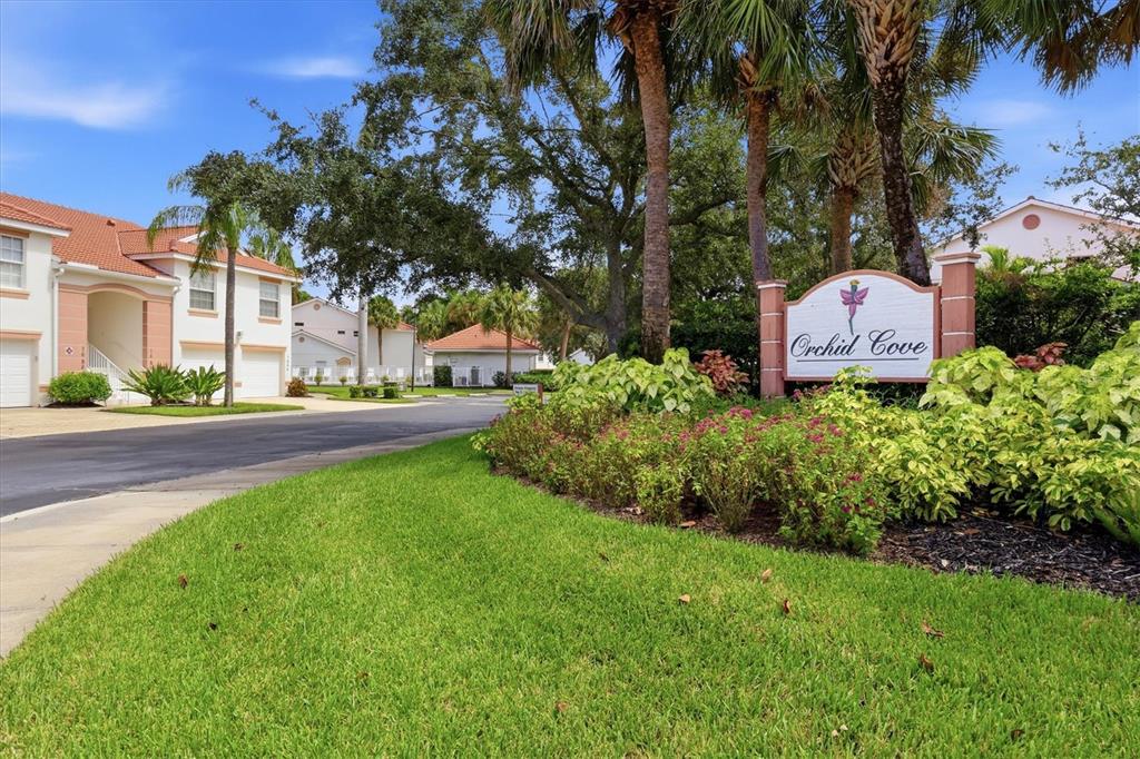 Aerial view of a residential community with red-roofed buildings, a swimming pool, and surrounding greenery — 7644 MARSH ORCHID CIRCLE, BRADENTON, FL