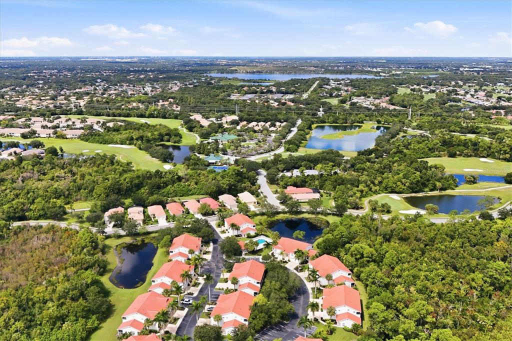 A kitchen with white cabinets and a stainless dishwasher overlooks a tiled living area — 7644 MARSH ORCHID CIRCLE, BRADENTON, FL