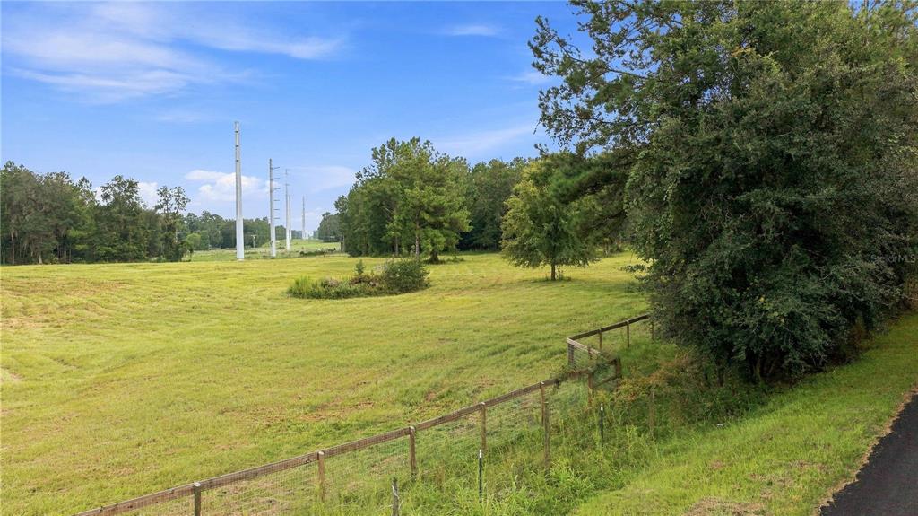 A grassy field with a wire fence and utility poles under a blue sky — 18601 NW 160TH AVENUE, WILLISTON, FL