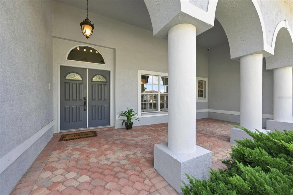 A covered entryway features a brick paver floor, double front doors, and large white columns — 501 MANISHA PLACE, TARPON SPRINGS, FL