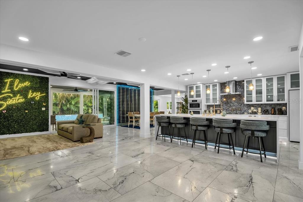 A spacious open-concept kitchen and living area features marble tile floors and a large island — 5624 CAPE LEYTE DRIVE, SARASOTA, FL