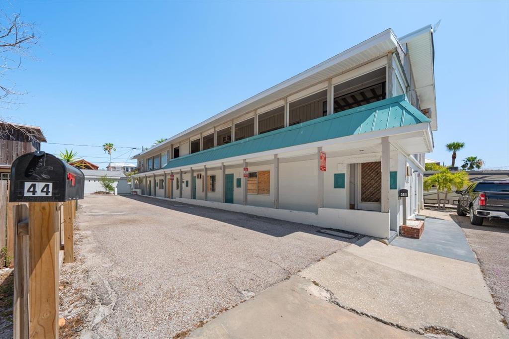 A multi-story exterior view of a building with a gravel parking lot and mailbox — 40 77TH AVENUE, TREASURE ISLAND, FL