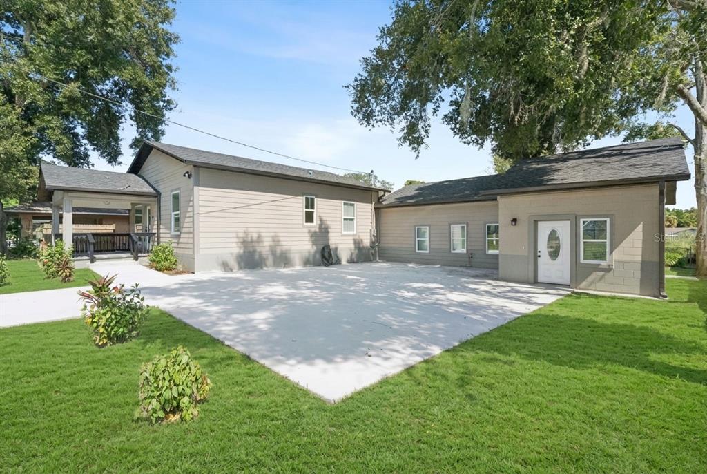 The exterior of a tan house features a large concrete driveway and a covered porch — 207 AVENUE E SE, WINTER HAVEN, FL