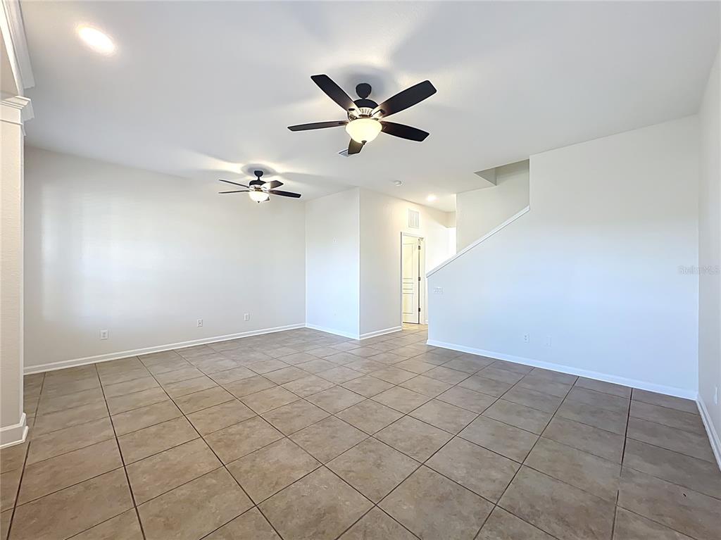 An empty room with beige tile flooring, white walls, and two ceiling fans — 12930 VENNETTA WAY, WINDERMERE, FL