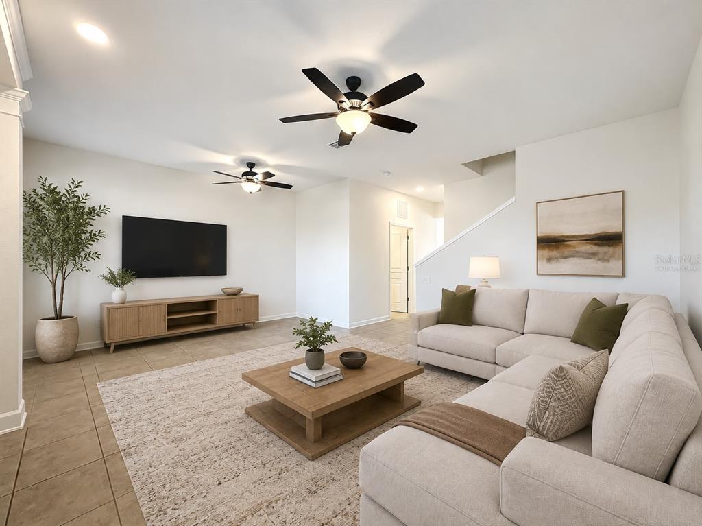 An empty room features light-colored tile flooring, two ceiling fans, and a white front door — 12930 VENNETTA WAY, WINDERMERE, FL