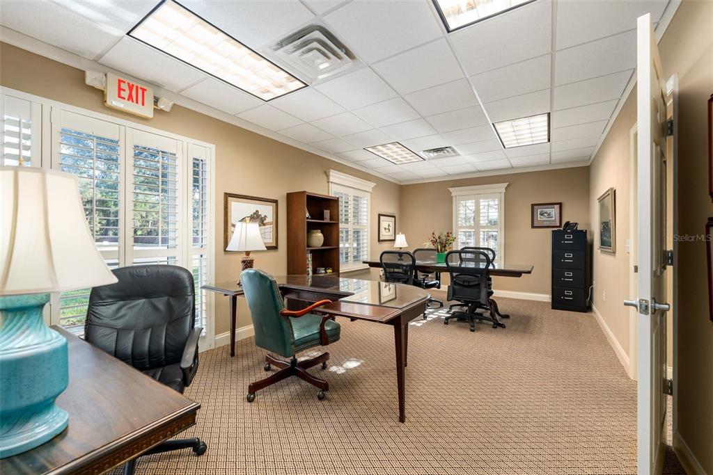 An office with beige walls, carpeted flooring, a glass-topped desk, and a conference table — 4110 NW 37TH PLACE UNIT A, GAINESVILLE, FL