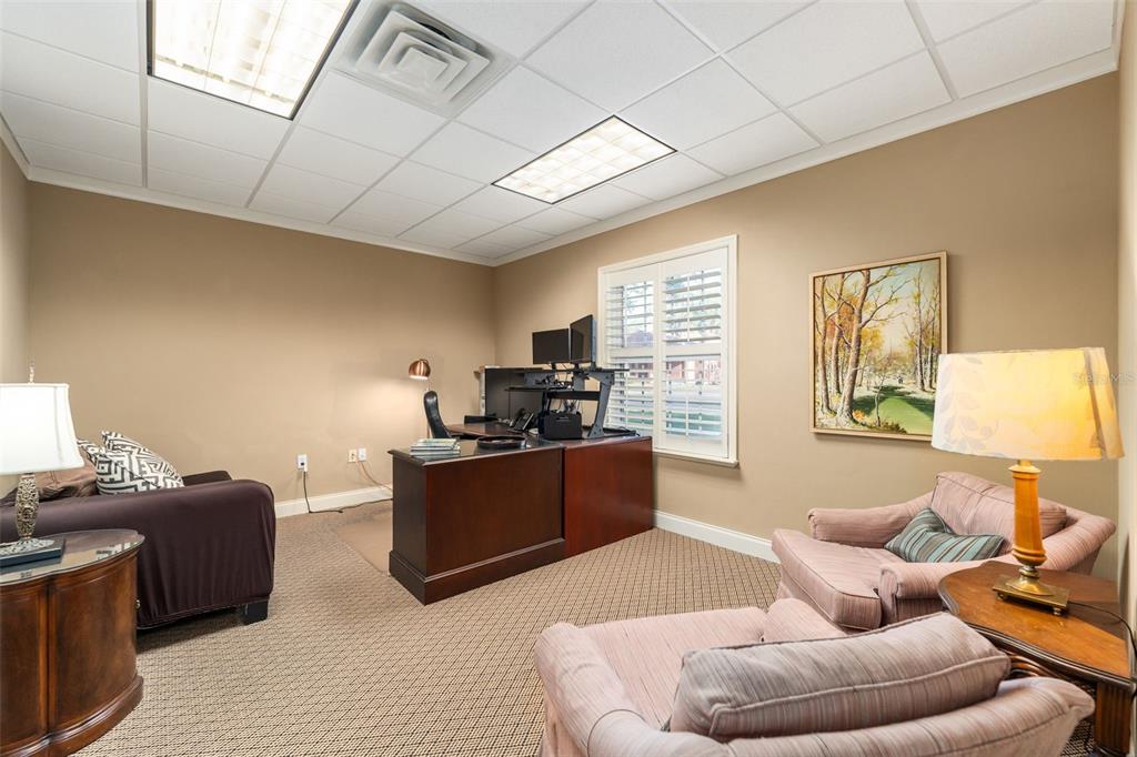 A home office features a dark wood desk, two armchairs, and a sofa on carpet — 4110 NW 37TH PLACE UNIT A, GAINESVILLE, FL