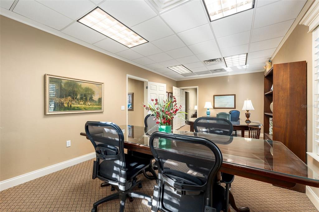 A professional office space features a glass-topped conference table, ergonomic chairs, and beige walls — 4110 NW 37TH PLACE UNIT A, GAINESVILLE, FL