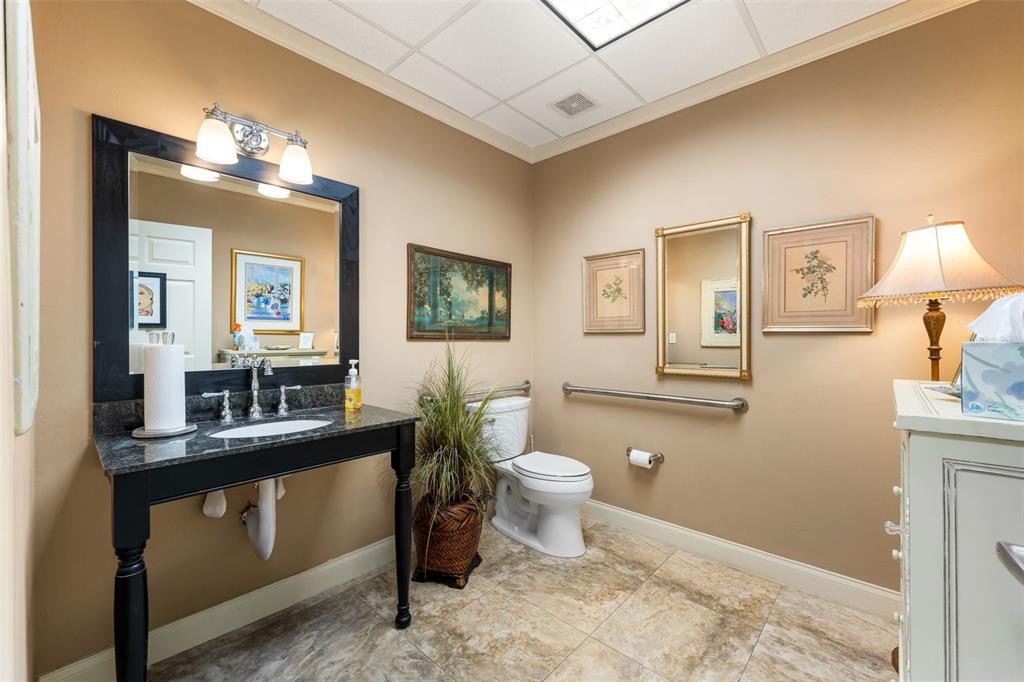 A bathroom features a dark vanity, a toilet with grab bars, and light-colored tile flooring — 4110 NW 37TH PLACE UNIT A, GAINESVILLE, FL