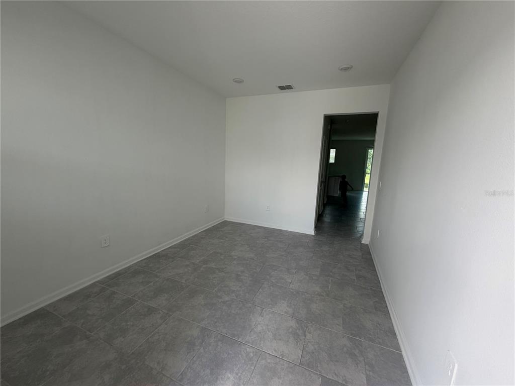 An empty room features white walls, recessed lighting, and gray tile flooring — 7429 STONE CREEK TRAIL, KISSIMMEE, FL