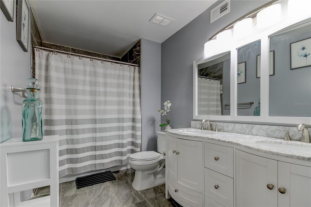 A kitchen with white cabinets and a breakfast bar opens into a living room area — 2400 FEATHER SOUND DRIVE UNIT 1228, CLEARWATER, FL