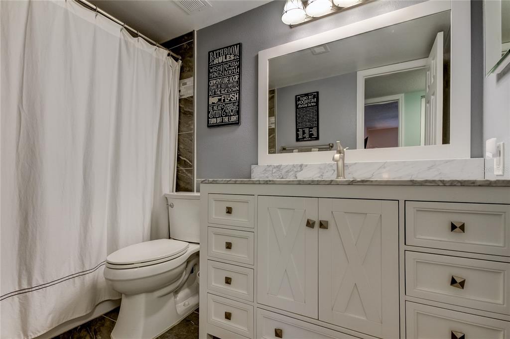 A kitchen features white cabinets, a stainless steel sink, and a breakfast bar — 2400 FEATHER SOUND DRIVE UNIT 1228, CLEARWATER, FL