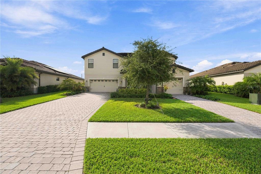 A two-story suburban house with a paved driveway, a front lawn, and a central tree — 17635 POLO TRAIL, BRADENTON, FL