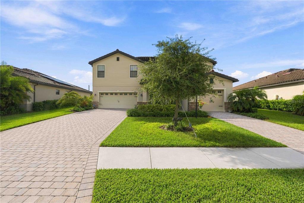 A two-story suburban house with a paved driveway, a front lawn, and a large tree — 17635 POLO TRAIL, BRADENTON, FL