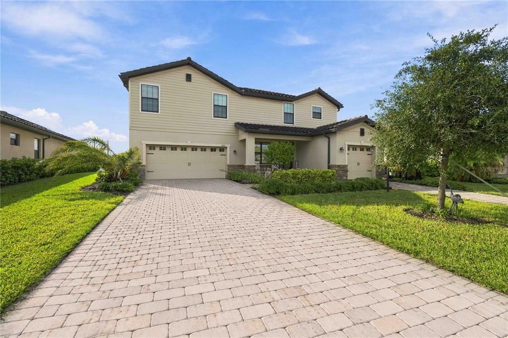 A two-story suburban house with a beige exterior, a paved driveway, and a three-car garage — 17635 POLO TRAIL, BRADENTON, FL