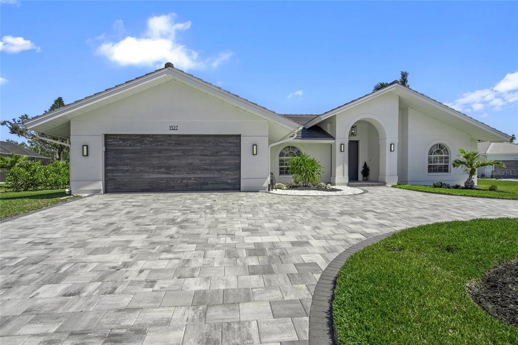 A white house with a gray garage door and a paved driveway under a blue sky — 1527 BUOY LANE, OSPREY, FL